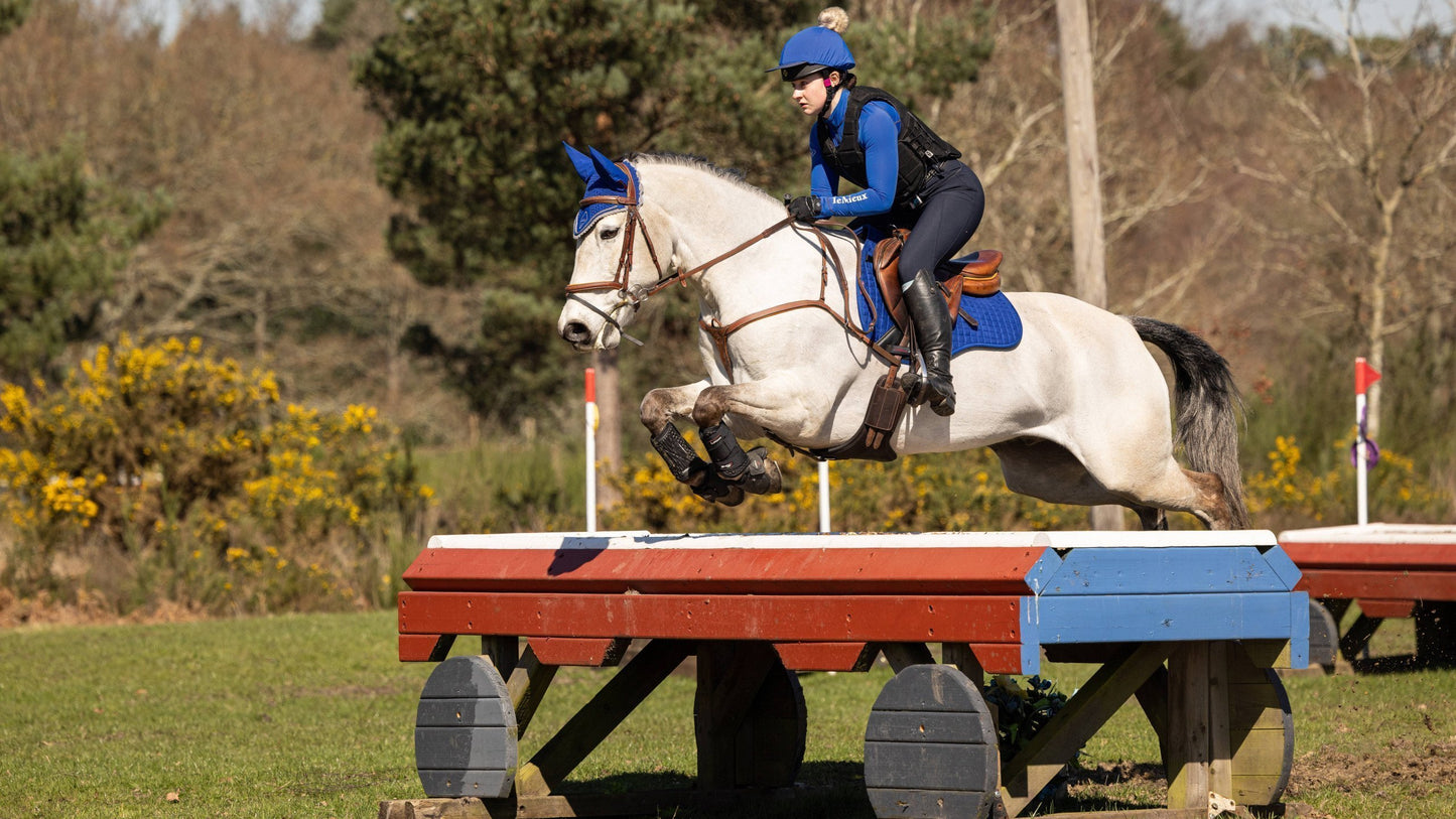 LeMieux Zadeldekje Suede GP Square Marine. Dit LeMieux Zadeldekje is verkrijgbaar bij Livin Horse Shop. Zijaanzicht springend paard en LeMieux Zadeldek Marine