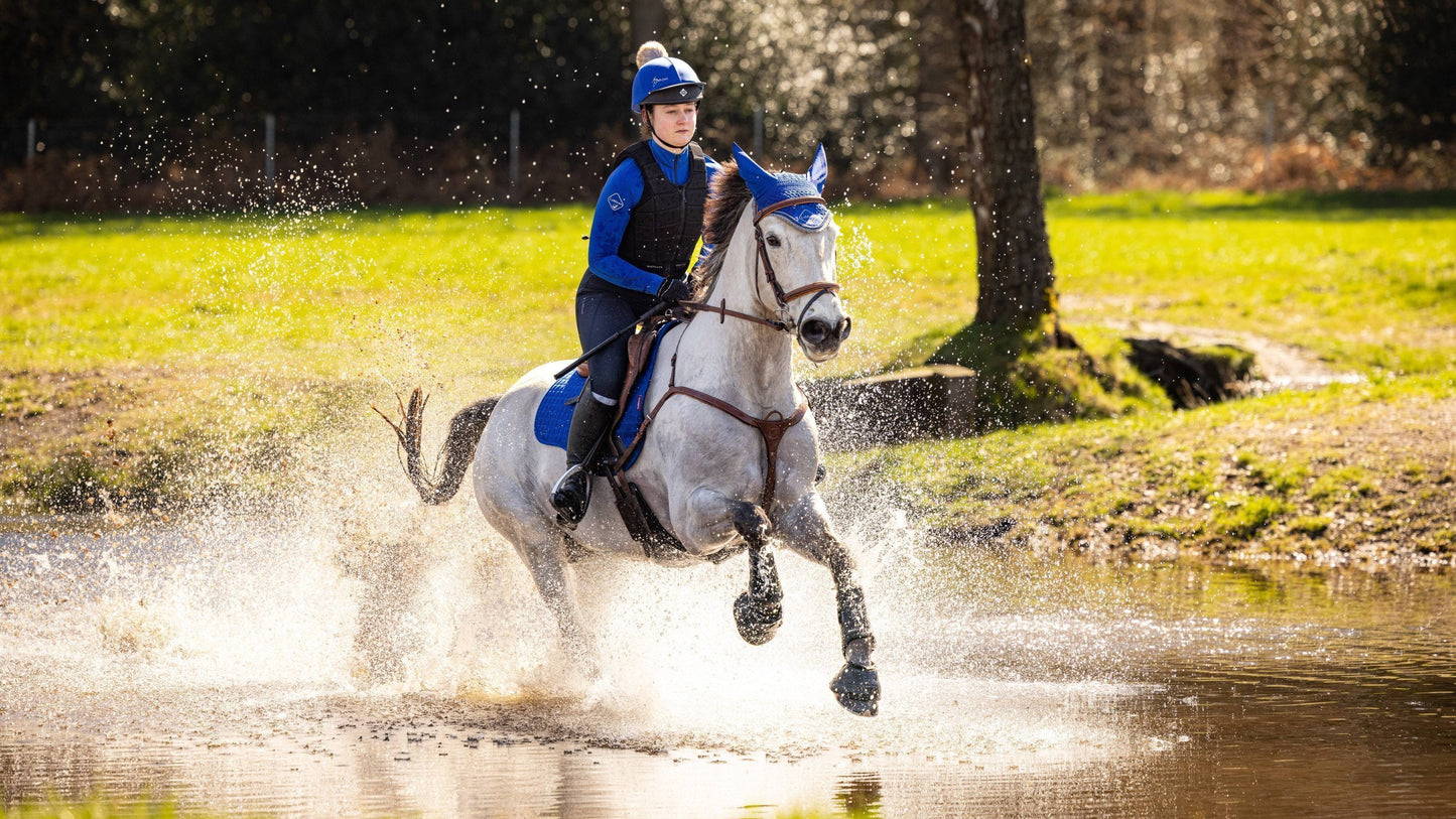 LeMieux Zadeldekje Suede Veelzijdigheid Square Benetton Blue. Dit trendy LeMieuz Zadeldekje is verkijgbaar bij Livin Horse Shop - zadeldek - zadeldekje - zadeldekje paard - zadeldekje pony. Zijaanzicht paard door waterbak en LeMieux Zadeldekje Benetton Blue